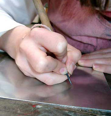 Foto einer Hand, die mit einer Radiernadel in eine Zinkplatte ritzt